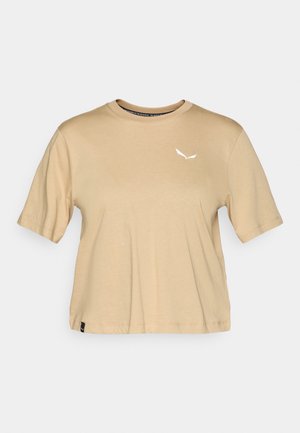 Beige Baumwoll-T-Shirt mit kurzen Ärmeln. Verfügt über einen runden Ausschnitt und ein weißes Logo auf der Brust. Gerader Saum mit einem dezenten Etiketten-Detail.
