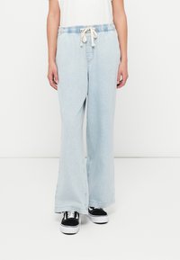 Világoskék, bőszárú farmernadrág gumis derékrésszel és húzózsinórral. Elülső zsebekkel és kényelmes szabással rendelkezik, sima textúrával.