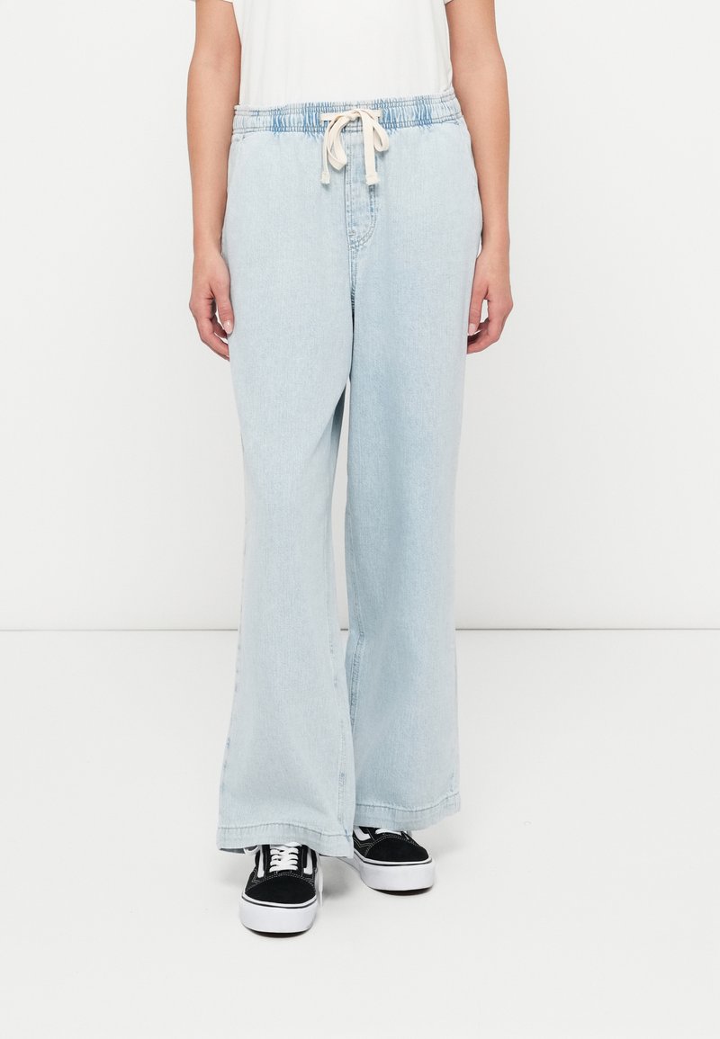 Pantaloni largi din denim albastru deschis cu talie elastică și șnur de strâns. Include buzunare frontale și croială casual cu textură netedă.