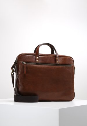 Brown leather bag with a smooth texture, dual top handles, a detachable shoulder strap, and a front zip pocket. Minimalist design.
