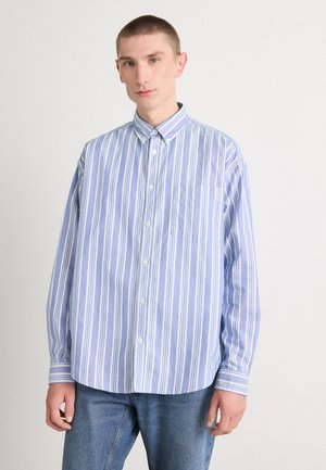 Striped button-up shirt in light blue and white, featuring a pocket, long sleeves, and a relaxed fit. Fabric has a smooth texture.