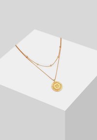 Gouden gelaagde ketting met een ronde hanger met een reliëf ontwerp van de zon, fijne kettingen met kleine ronde accenten.