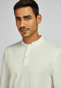 Helleckige, langärmlige Poloshirt mit Stehkragen, Drei-Knopf-Leiste und dezent strukturiertem Stoff. Gesticktes Logo auf der Brust.