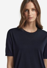 Mörkblå kortärmad t-shirt med rund halsringning, ribbad krage och mjuk textur. Har en avslappnad passform och en slät yta.