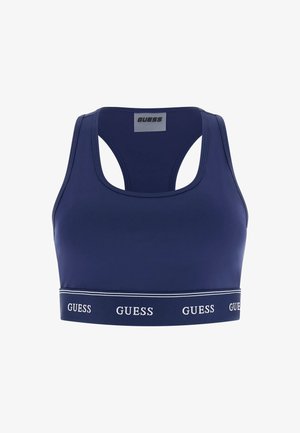Sujetador deportivo azul marino con diseño de espalda cruzada y banda elástica en la parte inferior con el logo "GUESS" repetido en letras blancas.