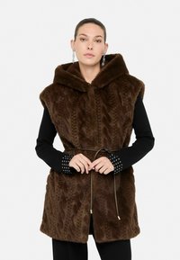 Gilet in finta pelliccia marrone con un design a maglia a treccia testurizzata, cappuccio e vita cintrata. Maniche lunghe nere con polsini borchiati.