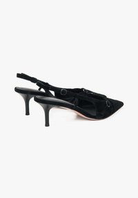 Czarne zamszowe szpilki slingback z ostrymi noskami, smukłymi obcasami w kształcie stiletto oraz okrągłymi akcentami metalowymi na paskach. Fakturowana cholewka.