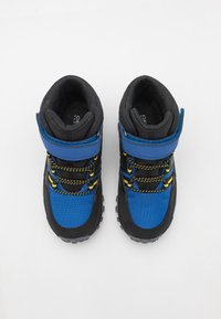 Modré a černé turistické boty s polstrovaným límcem, suchým zipem, žlutými akcenty, strukturovanou tkaninou a robustní gumovou podrážkou.