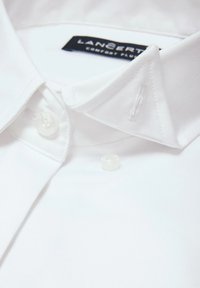 Biała koszula z kołnierzykiem o gładkiej fakturze, wyposażona w dwa przezroczyste guziki oraz metkę z napisem "LANCERTI COMFORT PLUS" na wewnętrznej stronie kołnierza.