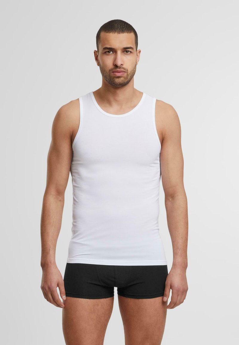 Top de algodón blanco sin mangas con tirantes amplios, diseño ajustado. Combinado con pantalones cortos negros de boxeador, textura lisa, mínima marca.