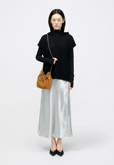 Mustat ylipitkät hupparit, pitkähihainen paita alla, hopeinen satiinihame, mustat kärkitossut ja ruskea nuppineulapussi. Siisti minimalistinen muotoilu.