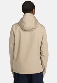 Beige wasserdichte Jacke mit Kapuze, elastischen Bündchen und geradem Saum. Glatte Textur mit minimalistischem Design, geeignet für verschiedene Aktivitäten.