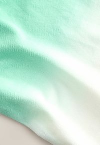 Lehká tkanina ukazující gradient od mátově zelené po bílou. Hladký povrch s jemným pleteným vzorem, vytvářející měkký vzhled.