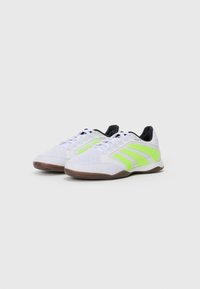 White indoor sports shoes with neon green stripes, black inner lining, and gum rubber soles, shown side by side on a white background.
