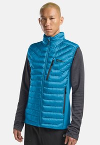 Gilet isolante blu con zip frontale, motivo a zig-zag e maniche lunghe di un grigio scuro a contrasto. Presenta un logo del marchio e tasche laterali.