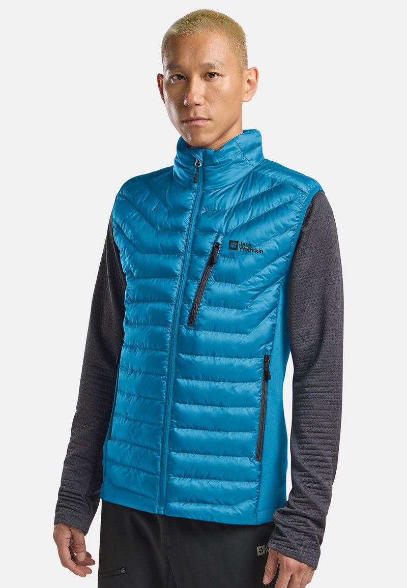 Gilet isolante blu con zip frontale, motivo a zig-zag e maniche lunghe di un grigio scuro a contrasto. Presenta un logo del marchio e tasche laterali.