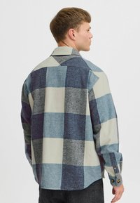 Kariertes Hemd aus weichem Baumwollstoff. Merkmale große cremefarbene, blaue und graue Karomuster, Knopfmanschetten und einen spitzen Kragen.