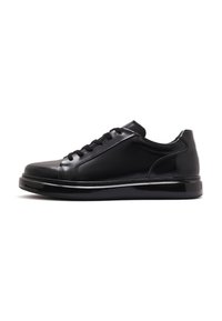 Black leather sneakers with a glossy finish, rounded toe, thick sole, and lace-up closure. Minimal stitching and a sleek silhouette.