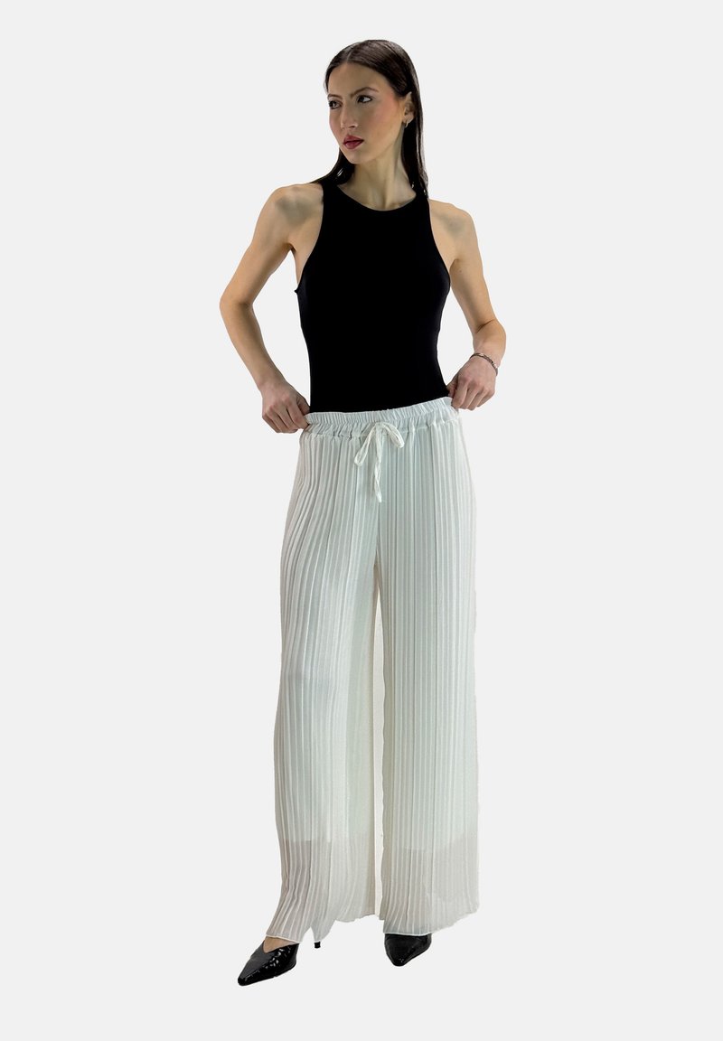 Witte geplooide wijde broek met een elastische tailleband en trekkoord. Combinatie met een zwarte mouwloze top en zwarte puntige hakken.