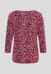 Langärmliges Oberteil mit abstraktem Muster in Rot, Lila, Weiß und Schwarz auf hellgrauem Hintergrund.