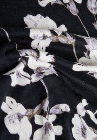 Black fabric featuring a floral pattern in white and light purple, with a smooth texture and soft drape, showcasing intricate flower details.
