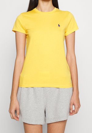 T-shirt en coton jaune à manches courtes et encolure ronde, avec un petit logo bleu sur la poitrine à gauche.