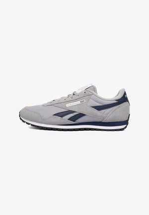 Pantof sport Reebok gri și bleumarin cu partea superioară din piele întoarsă și plasă, mijloc alb al tălpii, talpă exterioară neagră și logo Reebok pe lateral și pe călcâi.