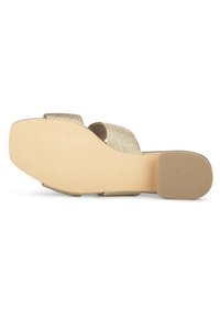 Flache Sandale mit breiten, gewebten goldenen Riemen und einer Gummisohle. Die Unterseite zeigt ein strukturiertes Muster für besseren Halt, mit einer abgerundeten, schmalen Form.