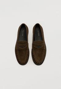 Brune semskede loafers med en sydd design og en flad sål. Fås med et frontbånd med mærkenavnet "GUESS" i metallisk skrift.