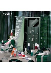 Boîte cadeau verte contenant plusieurs flacons de vernis à ongles de différentes couleurs. Comprend une tasse en cristal, un miroir et un ruban décoratif.