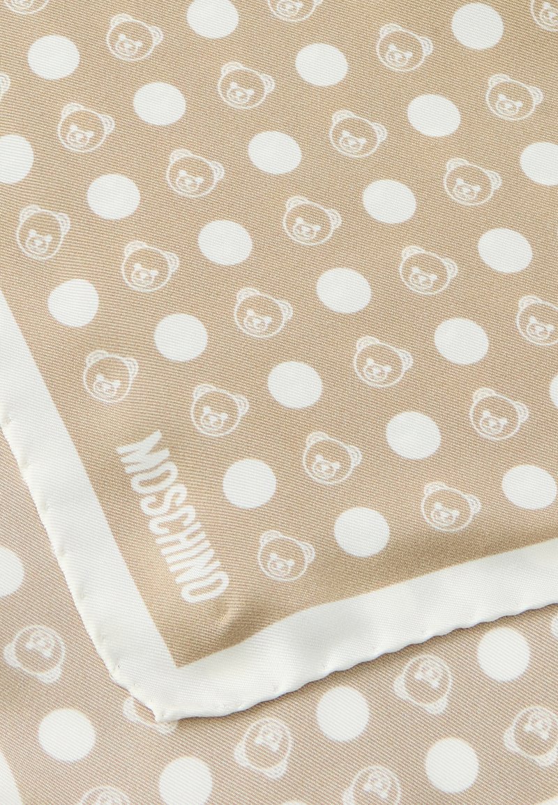 Beige silk scarf with a repeating pattern of white circles and bear faces. Features a white trim with "Moschino" printed in black.