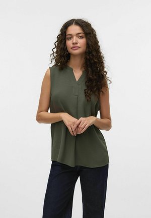 Ærmeløs bluse i olivengrøn med v-hals, afslappet pasform og blød tekstur, parret med mørke brede jeans.