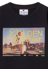 Zwarte katoenen t-shirt met een kleurrijke grafische print met de woorden "GOLDEN Hour" en "2024 SKATE PARK," aangevuld met gele accenten.