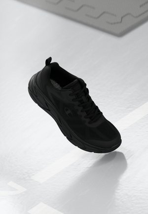 Baskets de sport noires avec une tige en mesh, une semelle texturée et une languette à l'arrière. Le design est épuré avec un branding subtil.