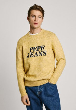 Suéter amarillo de punto con el logo en navy "PEPE JEANS" en la parte frontal. Cuello redondo, puños y dobladillo acanalados, combinado con jeans de mezclilla azules.