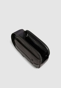 Zwarte leren tas met een gladde textuur, voorzien van twee met rits afgesloten vakken, waarvan één gevoerd met stof, en een logo aan de voorkant.