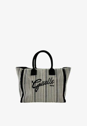 Borsa a tracolla in tessuto a righe con manici neri, bordi neri sfrangiati e ricamo "Gaelle Paris" in nero al centro davanti.