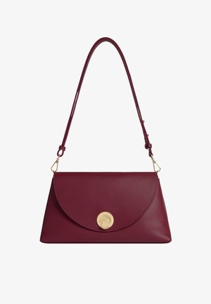 Borsa in pelle bordeaux con una pattina arrotondata e una chiusura circolare dorata. Dotata di una sola tracolla regolabile. Texture liscia.