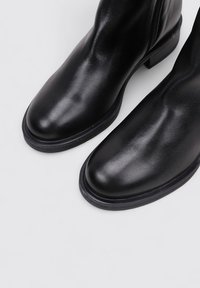 Black leather ankle boots with a smooth texture, rounded toe, and low block heel. Features a side zipper for easy wear.