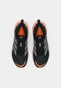 Scarpe da corsa nere con motivo strutturato, con strisce grigie, un accento arancione e suola rosa. Comprendono lacci e linguette per tirare.