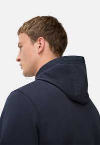 Marine hoodie met een contrasterende stof capuchon, gladde textuur en gestructureerd ontwerp. Heeft een hoge kraag en minimalistische branding.