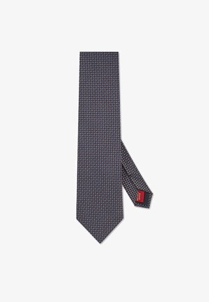Granatowy krawat z małym geometrycznym wzorem w kolorze białym i czerwonym. Gładka tkanina, wąski kształt, z metką widoczną z tyłu.