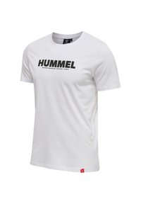 Vit T-shirt i bomull med korta ärmar, med en svart "HUMMEL"-logotyp och texten "SPORTSWEAR SINCE 1923" på framsidan. Röd accentetikett vid fållen.