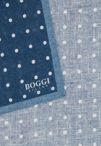 Mouchoir en coton bleu à pois blancs sur un fond en lin texturé, avec une bordure marine et le logo "BOGGI MILANO".