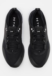 Ett par svarta sportskor med snören, vita öglor och dämpade sulor sedda ovanifrån på en vit bakgrund.