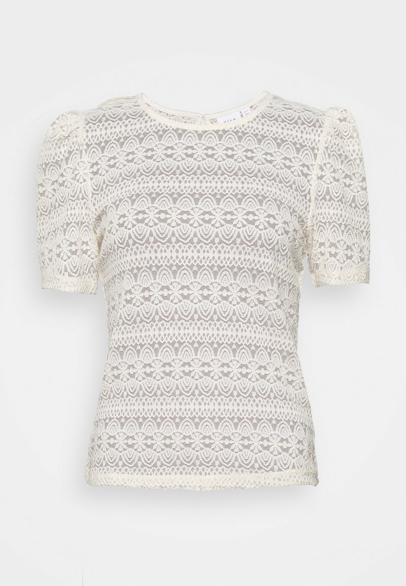 Blusa de encaje con mangas cortas abullonadas, de color crema, con intrincados patrones florales y un escote redondeado. Incluye detalles de cierre en la parte posterior.