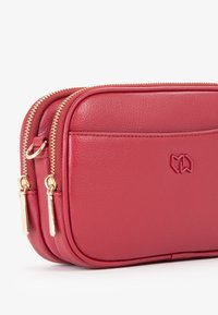 Borsetta a tracolla in pelle rossa con finitura testurizzata, presenta due scomparti con cerniera e accessori in metallo dorato, logo in rilievo sulla parte anteriore.