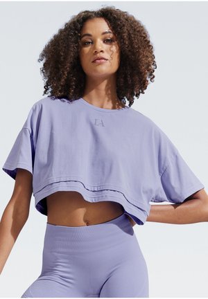 Cropped purple t-shirt made of soft material with short sleeves and a round neckline, featuring a small "LA" logo embossed on the front.