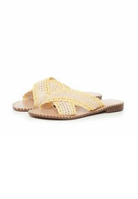 Sandalias trenzadas con un diseño en beige y amarillo, que cuentan con correas cruzadas y suelas planas, elaboradas con materiales naturales.