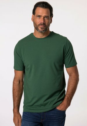 T-shirt verde a maniche corte realizzato in tessuto morbido con scollo rotondo, caratterizzato da una texture liscia e una vestibilità classica. Indossato con jeans di denim.